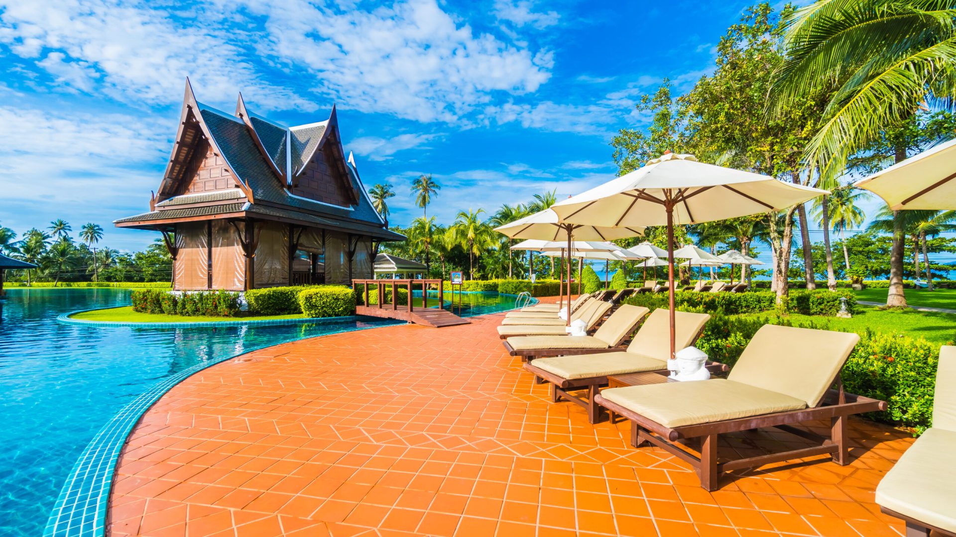 Beautiful luxury umbrella and chair around outdoor swimming pool in hotel and resort with coconut palm tree on blue sky - Boost up color Processing